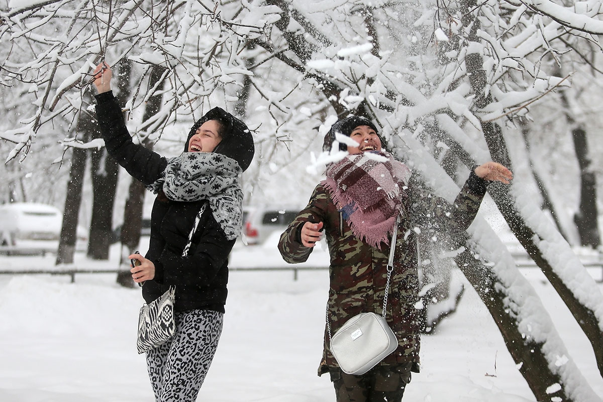 Москва теплая зима. Человек в снегопад. Зимняя погода. Люди радуются зимой. Снегопад в Москве сегодня.